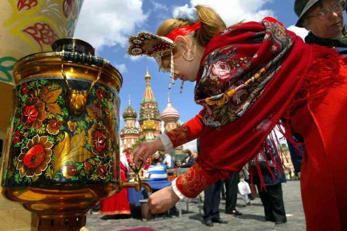 Gadis Rusia yang mengenakan pakaian tradisional menuangkan air dari samovar