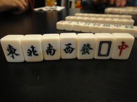 Angin dan naga ubin dalam satu set mahjong berdiri tegak di atas meja.