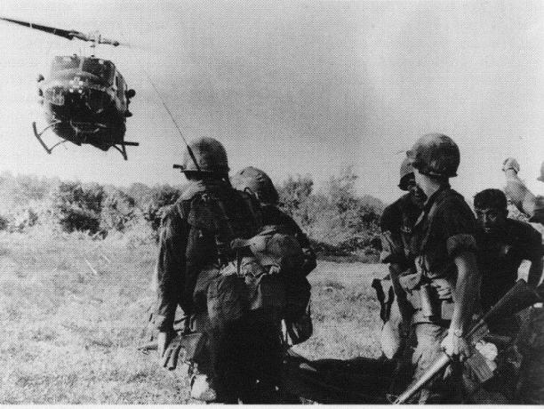 Helikopter UH-1 Huey mendarat di dekat sekelompok tentara.