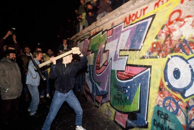 Seorang pria menyerang Tembok Berlin dengan beliung pada malam 9 November 1989