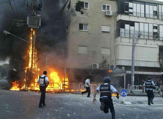 Polisi Israel bergegas ke tempat tiang listrik terbakar dan merusak bangunan beberapa saat setelah tembakan roket Hizbullah menghantam 13 Juli 2006 di kota utara Nahariya, Israel.