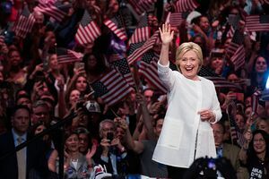 Hillary Clinton melambai di depan kerumunan orang yang mengibarkan bendera A.S.