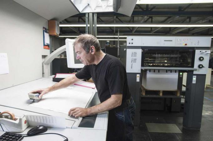 Pekerja menyiapkan peralatan pencetakan digital di bengkel cetak