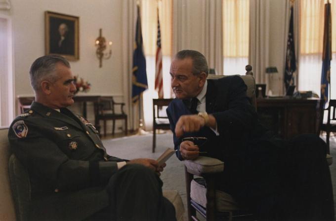 Jenderal William Westmoreland, dalam seragam Angkatan Darat AS dan duduk, berbicara dengan Presiden Lyndon B. Johnson di Kantor Oval.