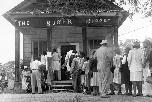 Pemilih Afrika-Amerika, yang dapat memilih untuk pertama kalinya di pedesaan Wilcox County, Alabama, berbaris di depan tempat pemungutan suara setelah pengesahan undang-undang hak suara federal pada tahun 1965.