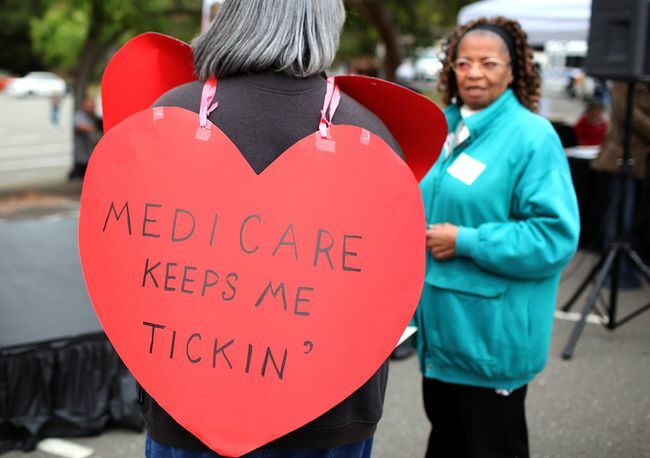 Wanita mengenakan tanda berbentuk hati bertuliskan 'Medicare Keeps Me Ticking'