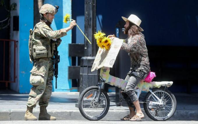 Seorang tentara Garda Nasional menerima sekuntum bunga dari pengunjuk rasa selama demonstrasi damai atas kematian George Floyd di Hollywood pada 3 Juni 2020.