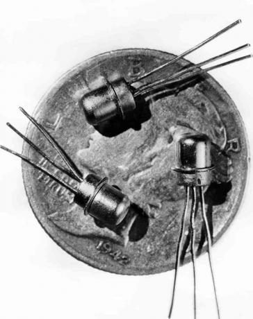 Gambar bertanggal 1956 dari tiga miniatur transistor M-1 terlihat pada permukaan uang receh
