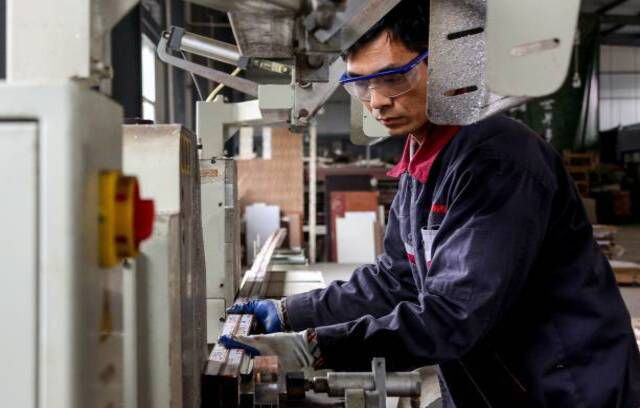 Seorang karyawan yang mengerjakan produk aluminium di sebuah pabrik di Zouping di provinsi Shandong timur China