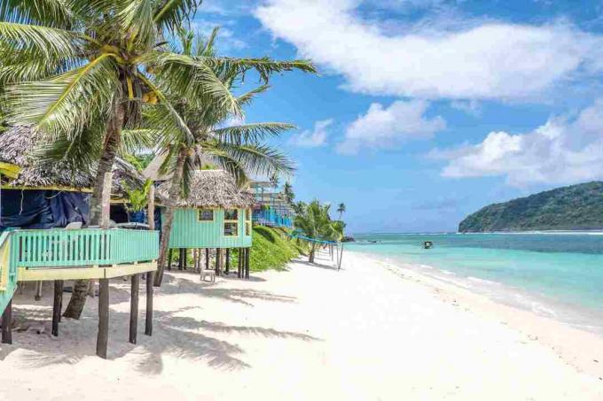 Pemandangan di sepanjang Pantai Lalomanu, Pulau Upolu, Samoa, gubuk-gubuk kecil pantai Samoa yang berwarna-warni yang merupakan alternatif dari akomodasi hotel atau resor