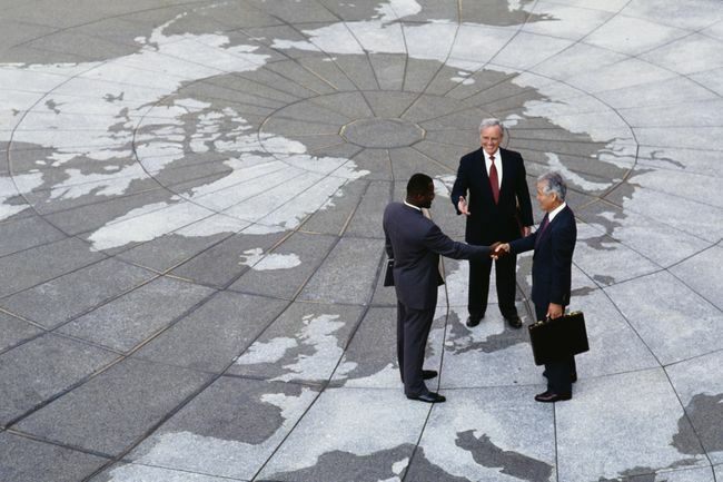  Regionalisme Ekonomi: Pengusaha berjabat tangan di peta dunia.