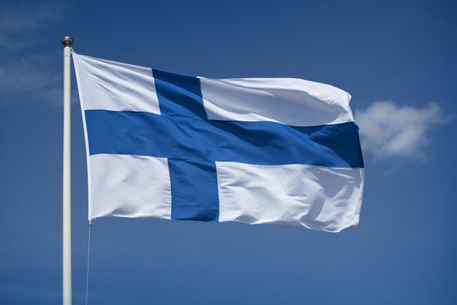 Mengibarkan bendera Finlandia dengan latar belakang langit biru