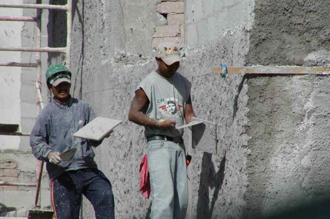 dua pekerja menerapkan lapisan plester dengan sekop