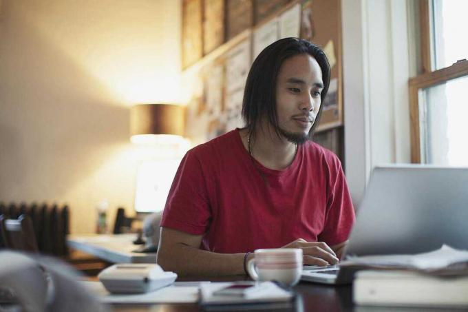 Orang menulis di laptop di meja.